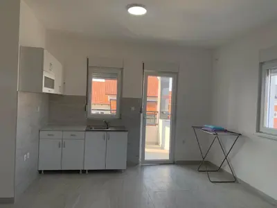 a kitchen with white cabinets and a table in it at Belgrade Airport Luxury Single in Surčin