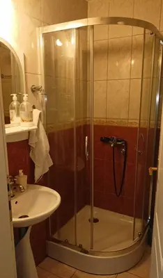 a shower with a glass door next to a sink at Ogi apartman in Belgrade