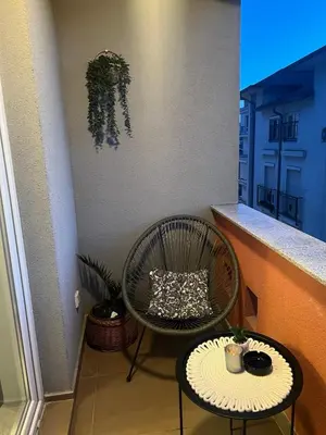 a small balcony with a chair and a table at Mona Lux apartman in Arandjelovac