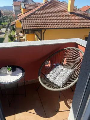 a rattan chair on a balcony with a grill at Mona Lux apartman in Arandjelovac
