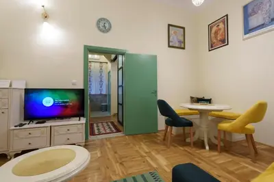 a living room with a table and chairs and a tv at Apartment Nedeljica in Belgrade
