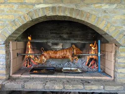 a cow is cooking in a brick oven at Vila Restart Čortanovci in Čortanovci