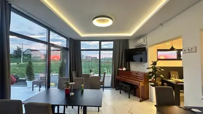 a living room with a table and a piano at KIMMIY Garni Attic Rooms near Belgrade Airport in Beograd