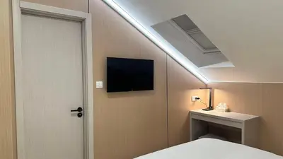 a room with a bed and a tv on the ceiling at KIMMIY Garni Attic Rooms near Belgrade Airport in Beograd