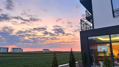 a building with a view of a field at sunset at KIMMIY Garni Attic Rooms near Belgrade Airport in Beograd