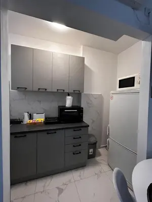 a kitchen with white cabinets and a refrigerator at Hyde park apartments in Belgrade