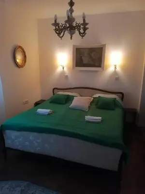 a bedroom with a green bed with a chandelier at Hyde park apartments in Belgrade