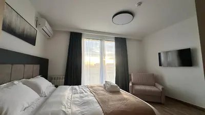 a bedroom with a bed and a chair and a window at KIMMIY HOTEL Garni in Beograd