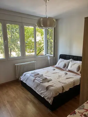 a bedroom with a bed in a room with windows at Apartment Duchess in Belgrade