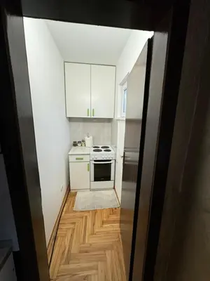 a small kitchen with white cabinets and a wooden floor at Stan na dan Borca in Belgrade
