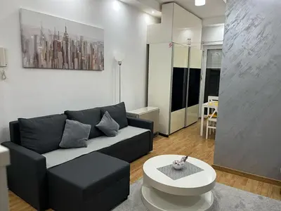 a living room with a black couch and a table at Studio apartment near the city center in Belgrade