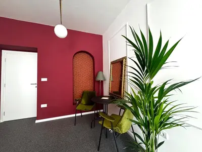 a room with a red wall and a table and a plant at Downtown Buzz Mili in Belgrade