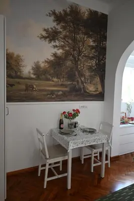 a dining room with a table and chairs and a painting at La Pastorela in Belgrade