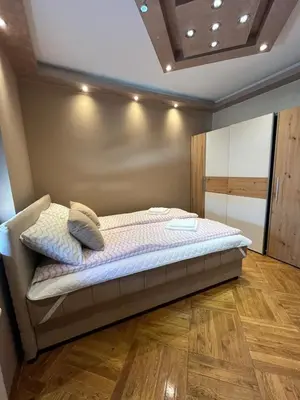a large bed in a room with a wooden floor at Apartman Miladinović in Belgrade
