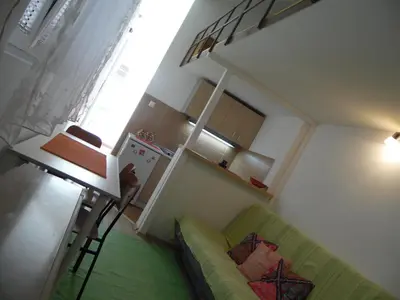 a living room with a green couch and a kitchen at Apartment Angie in Belgrade