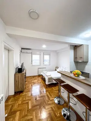 a room with a bed and a kitchen with a table at Limpio Apartman in Belgrade