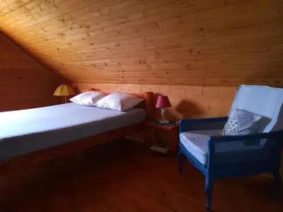 a bed and a chair in a room with wooden walls at Ranch V8 Kosmaj in Rogača