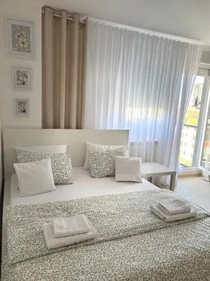 a bedroom with a large bed with pillows and a window at Apartment Leona in Inđija