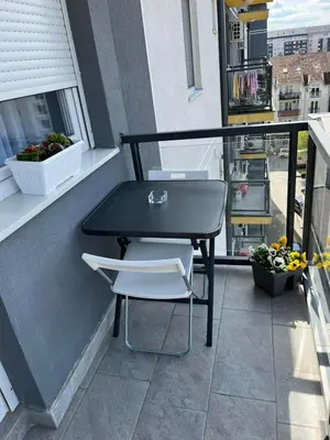 a black table and two white chairs on a balcony at Apartment Leona in Inđija