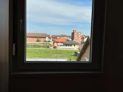 a window with a view of a field and buildings at Belgrade Airport single bed in Surčin