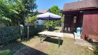 a picnic table with an umbrella next to a house at Wooden house Ada in Ada Ciganlija