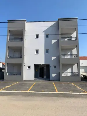 a white apartment building with a parking lot at Deluxe Belgrade Airport Single Room in Surčin