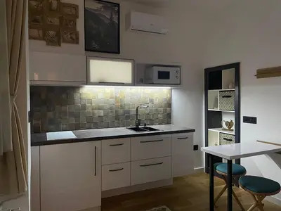 a kitchen with white cabinets and a sink and a table at Tiny Nest - Sava Center, Belgrade in Belgrade