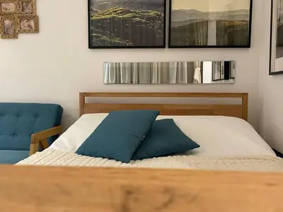 a bedroom with a bed and a blue chair at Tiny Nest - Sava Center, Belgrade in Belgrade