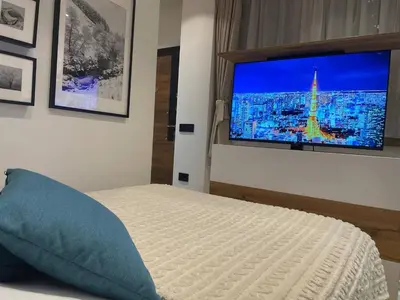 a bedroom with a bed with a large television on the wall at Tiny Nest - Sava Center, Belgrade in Belgrade