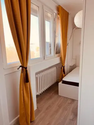 a bedroom with yellow curtains and a bed and two windows at Your cozy place! in Belgrade