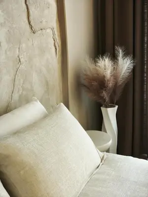 a bed with a pillow and a vase with feathers at Rossa & Bayo Apartments in Belgrade