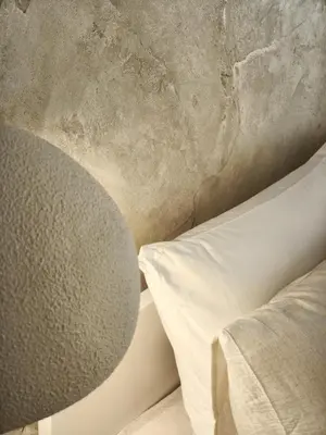 a bed with a white pillow next to a wall at Rossa & Bayo Apartments in Belgrade