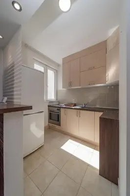 a kitchen with wooden cabinets and a tile floor at Apartman Igor 1 in Belgrade