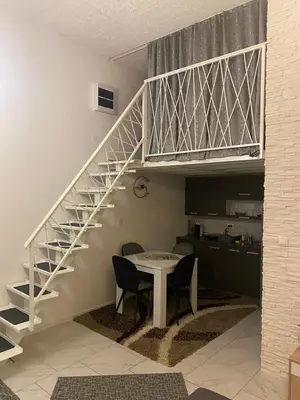 a staircase in a living room with a table and chairs at Galerija apartman in Arandjelovac