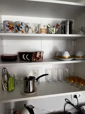 a kitchen shelf with dishes and cups and a pot on it at Galerija apartman in Arandjelovac