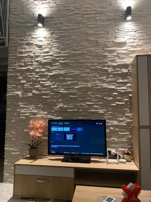 a computer monitor on a desk with a stone wall at Galerija apartman in Arandjelovac