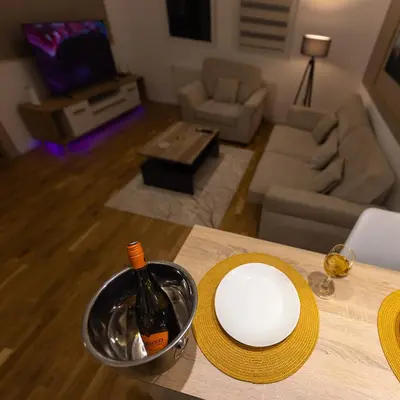 a bottle of wine and a plate on a table in a living room at Oaza Apartmani Jakovo AFRODITA in Jakovo
