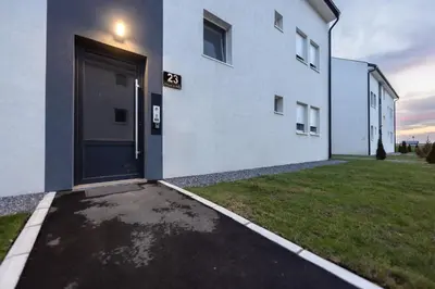 a white building with a large door on the side of it at Oaza Apartmani Jakovo AFRODITA in Jakovo