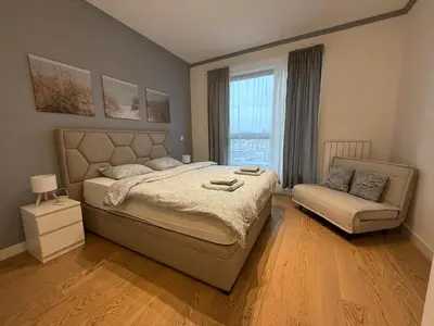 a bedroom with a bed and a couch and a window at Beograd na vodi Lux apartman BW Magnificent City View in Sajmište