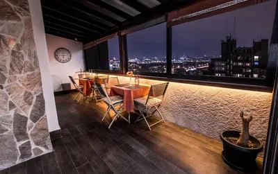 a dining room with a view of a city at night at Belgrade Penthouse - among the clouds in Belgrade