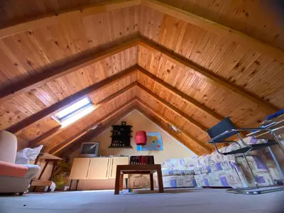 a room with a wooden ceiling with a couch and a table at Vikendica Lela in Beška