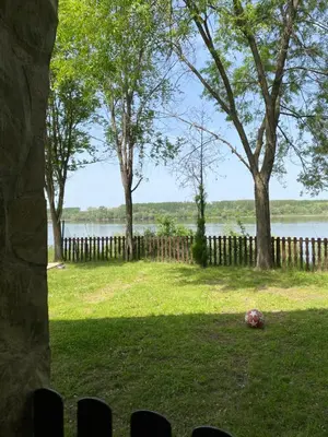 a yard with trees and a fence and a body of water at Vikendica Lela in Beška