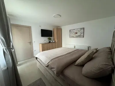 a bedroom with a large bed and a television at Kolonja Apartmani in Arandjelovac