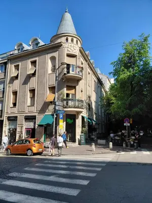 a building with a tower on a street with a car at World Traveler in Belgrade