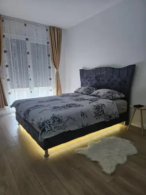 a bedroom with a bed with a blue comforter and a rug at Miss LUX in Mladenovac