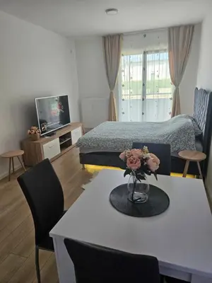a bedroom with a bed and a table with a vase of flowers at Miss LUX in Mladenovac