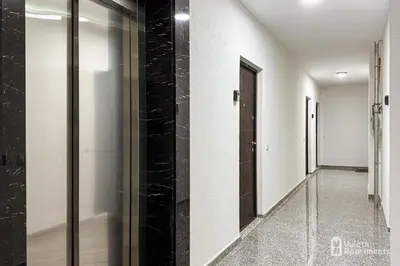 a hallway with black tile and glass doors at Vuleta Apartments Aranđelovac in Arandjelovac