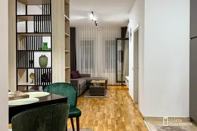 a living room with a couch and a table and chairs at Vuleta Apartments Aranđelovac in Arandjelovac