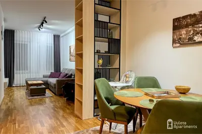 a living room with a table and green chairs at Vuleta Apartments Aranđelovac in Arandjelovac
