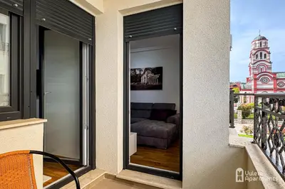 a sliding glass door with a couch on a balcony at Vuleta Apartments Aranđelovac in Arandjelovac